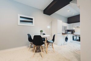 A modern kitchen with white cabinets, a built-in oven, and a washing machine.