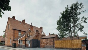A two-story brick house with a black gate and a wooden fence.
