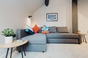 A modern living room with a grey sectional sofa, a small round table, and a potted plant.