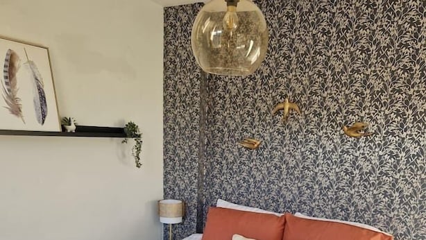 Ein Schlafzimmer mit einem Bett, einer Hängelampe und einer Wand mit Muster.