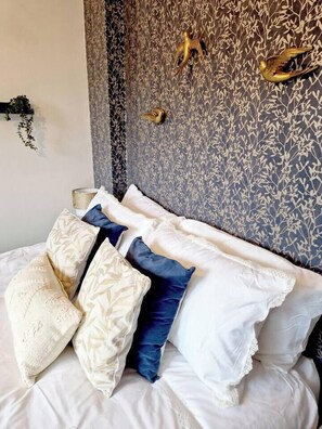 A bed with multiple pillows and a wall with a leaf pattern. - Coventry Home: Playroom & CBS Arena (West Midlands)