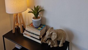 Ein gerahmtes Poster von Paris, ein gerahmtes Poster von New York, eine Lampe, eine kleine Pflanze und ein dekorativer Elefant auf einem schwarzen Tisch.