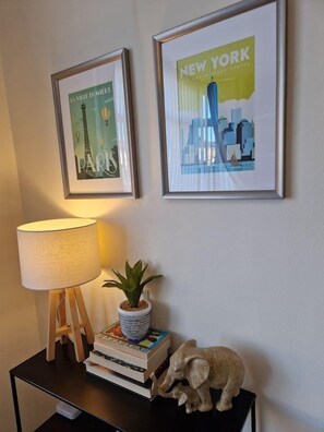 A framed poster of Paris, a framed poster of New York, a lamp, a small plant, and a decorative elephant on a black table. - Coventry Home: Playroom & CBS Arena (West Midlands)