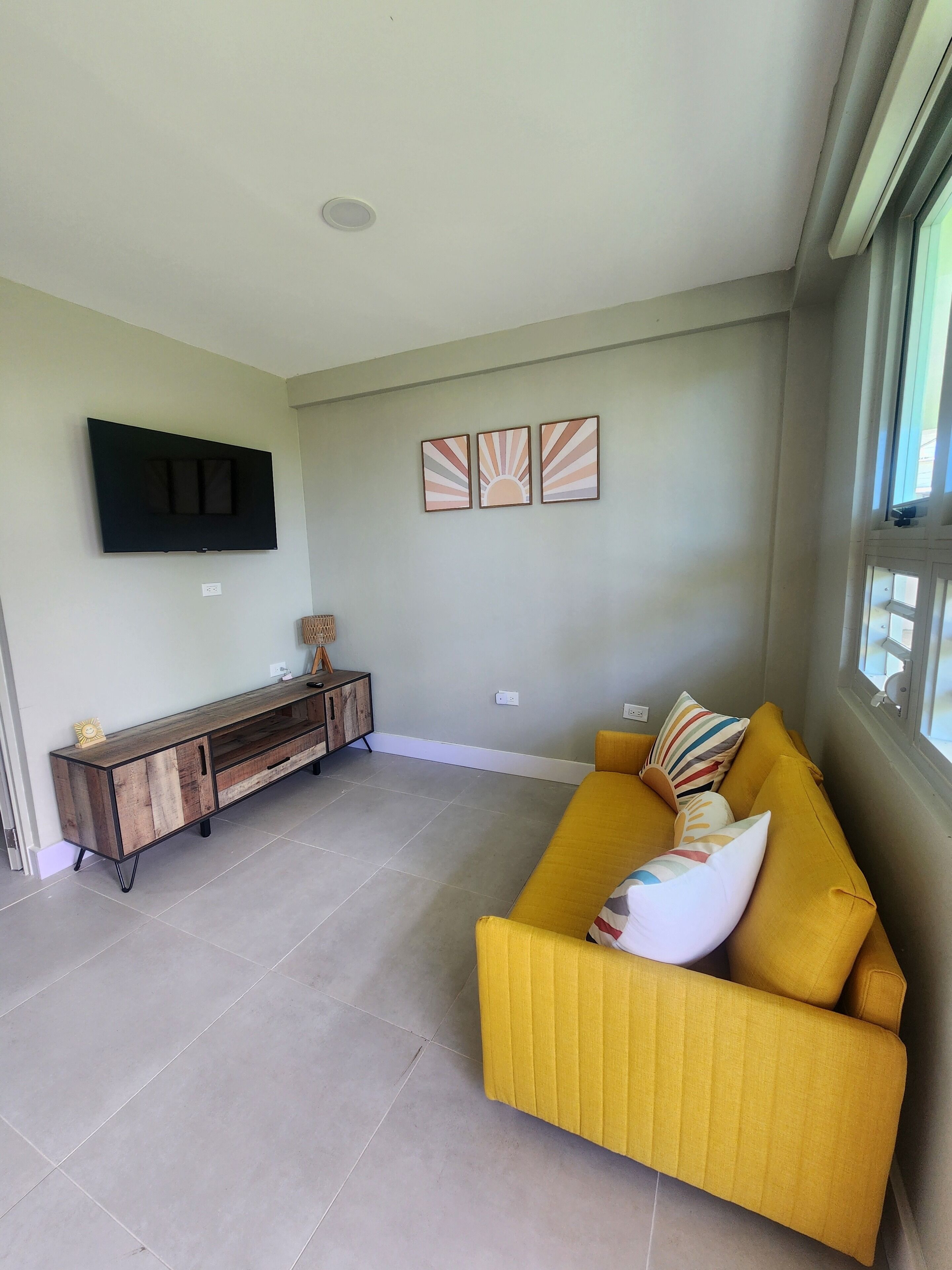 A living room with a sofa, a TV mounted on the wall, and a console table.