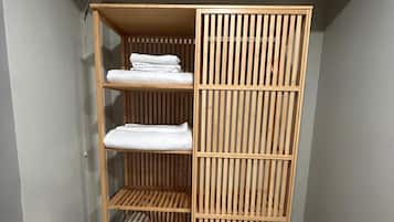 A wooden wardrobe with three shelves, a hanging rod, and a sliding door.