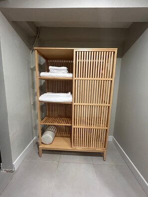 Un armadio in legno con tre ripiani, un'asta appendiabiti e una porta scorrevole.