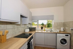 A compact kitchen with a microwave, toaster, sink, and washing machine.