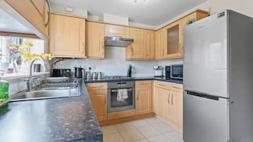 A modern kitchen with wooden cabinets, stainless steel appliances, and a marble countertop.