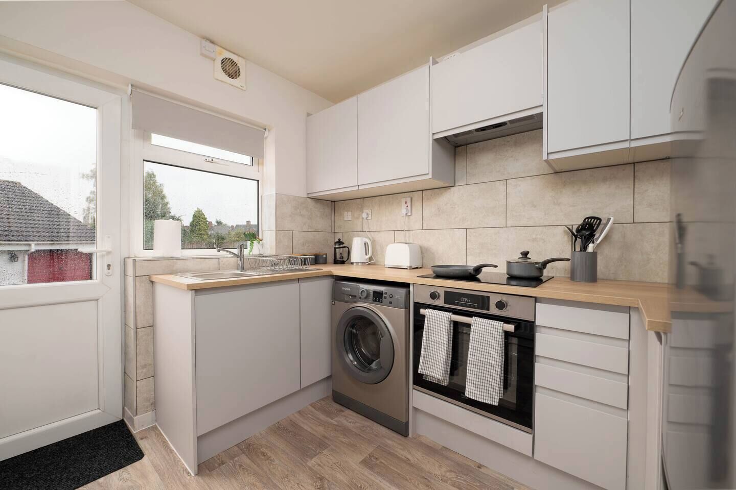 A compact kitchen with a washing machine, oven, and a small countertop area.