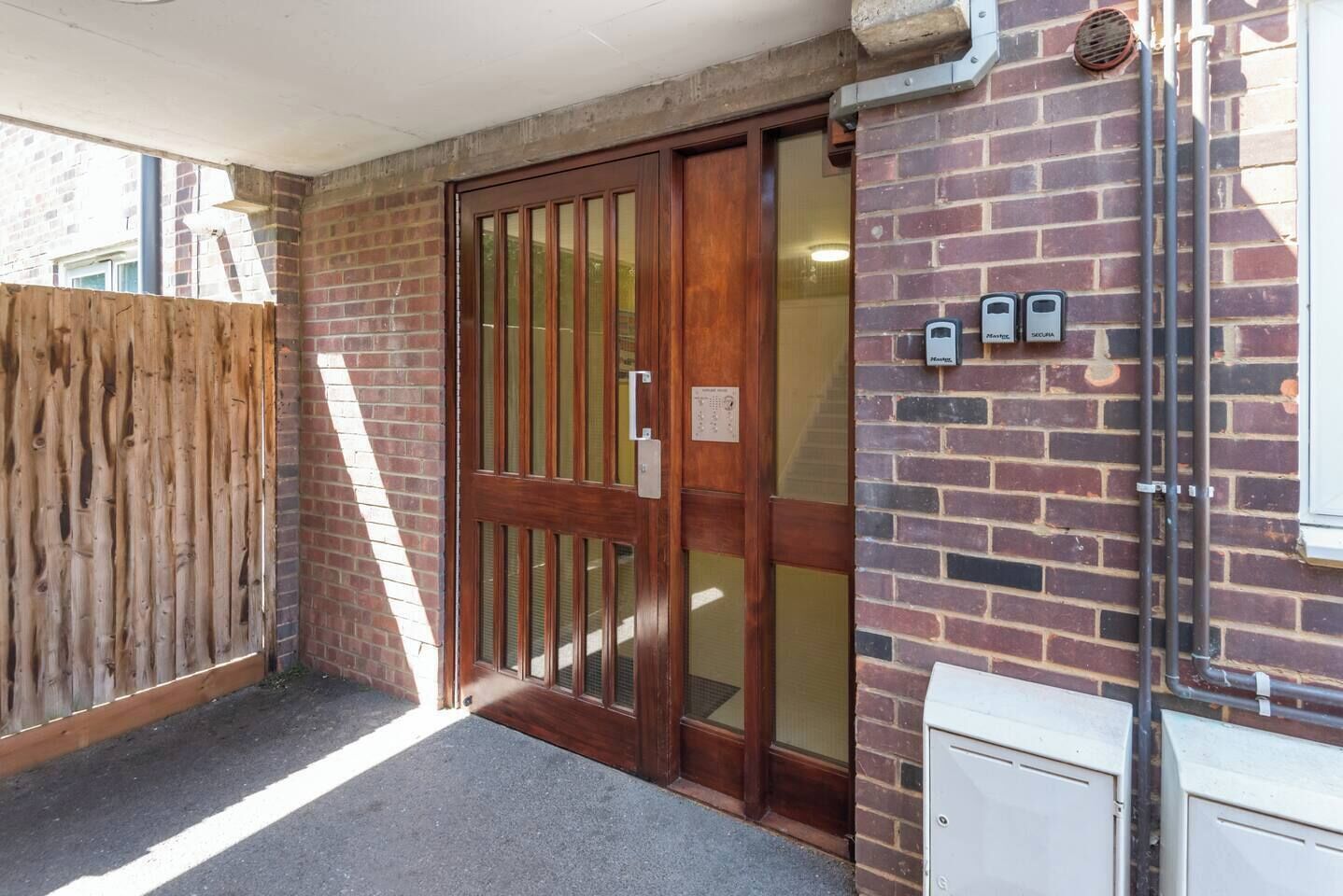 A wooden door with a glass panel, a brick wall, and a white utility box.
