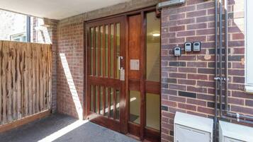A wooden door with a glass panel, a brick wall, and a white utility box.