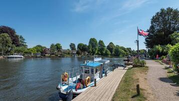 A river with boats docked, a wooden pier, and a flag.
