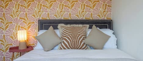 A bed with a headboard, pillows, and a bedside table with a lamp.