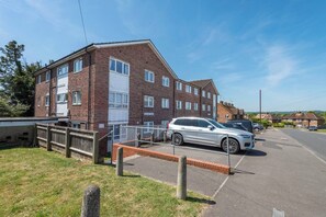 A multi-story residential building with a brick facade, a gated parking area, and a clear sky. - #30 Cozy & Stylish Studio Retreat (Wooburn Green)