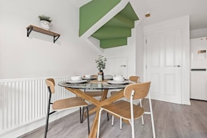 A dining area with a round table, four chairs, and a potted plant on a shelf. - #28 Luxury 5bdr house|sleeps 11|near Bullring (West Midlands)