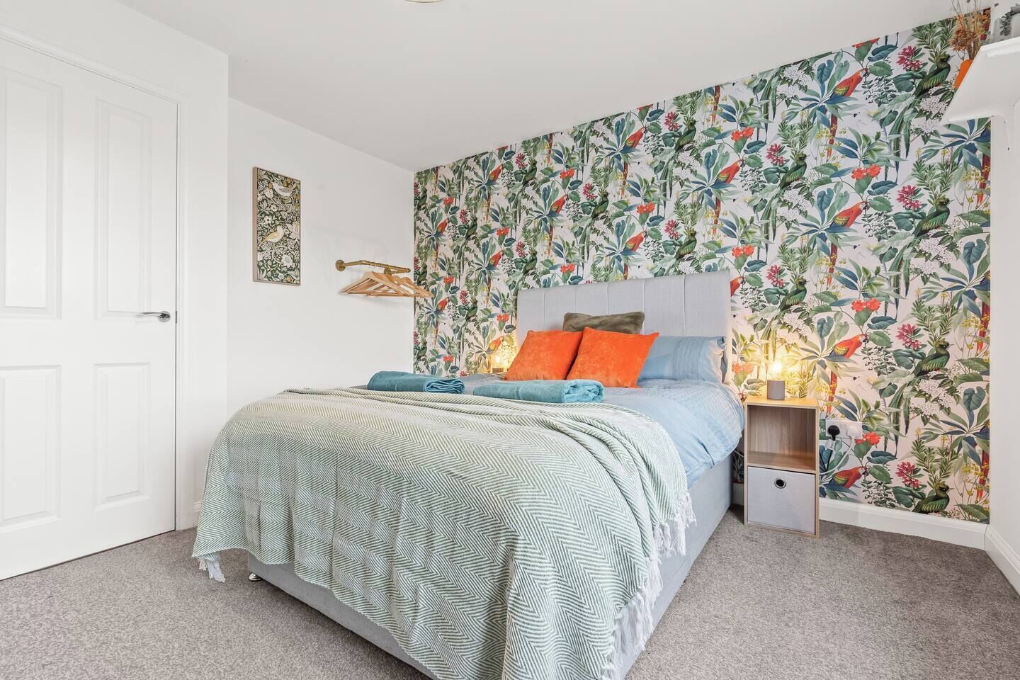 Ein Schlafzimmer mit einem Bett, einem Nachttisch, einer Wandlampe und einer Tür.