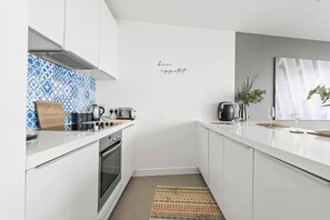A modern kitchen with white cabinetry, a blue patterned backsplash, and a stainless steel range hood. - #25 World Famous Rotunda 18th floor skyline views (West Midlands)