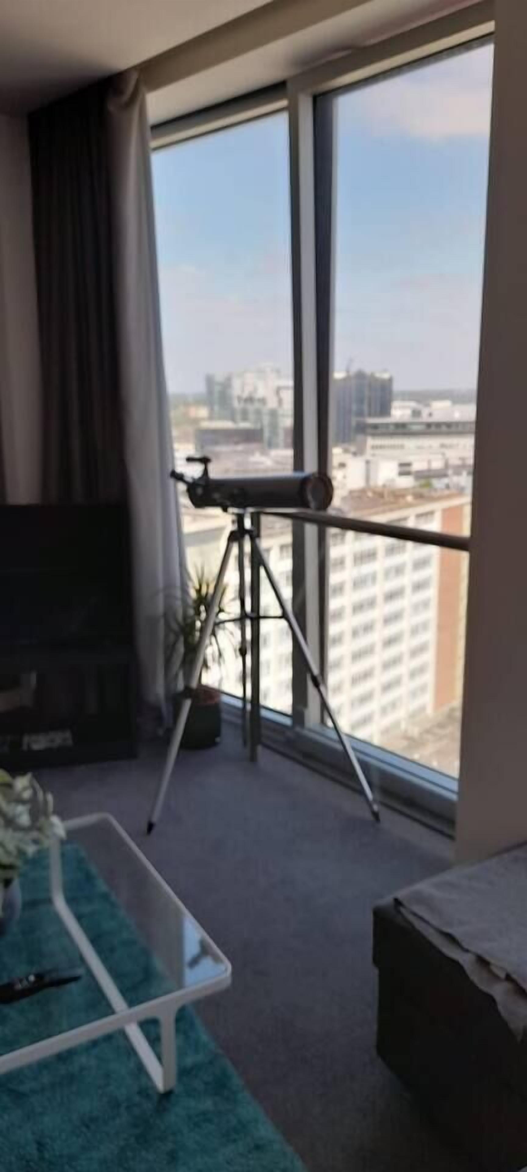 Een kamer met een groot raam, een statief en een klein tafeltje.