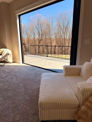 Ein Zimmer mit einer großen Schiebeglas-Tür, die auf eine Terrasse mit Blick auf kahle Bäume führt.