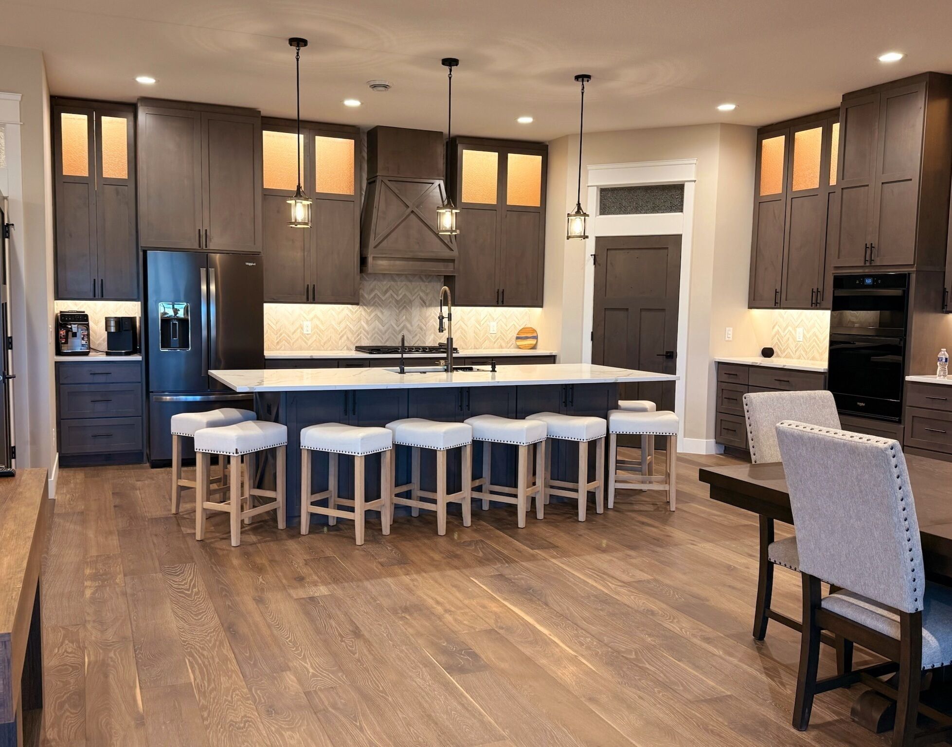 A modern kitchen with dark wood cabinets, a central island with bar stools, and pendant lighting.