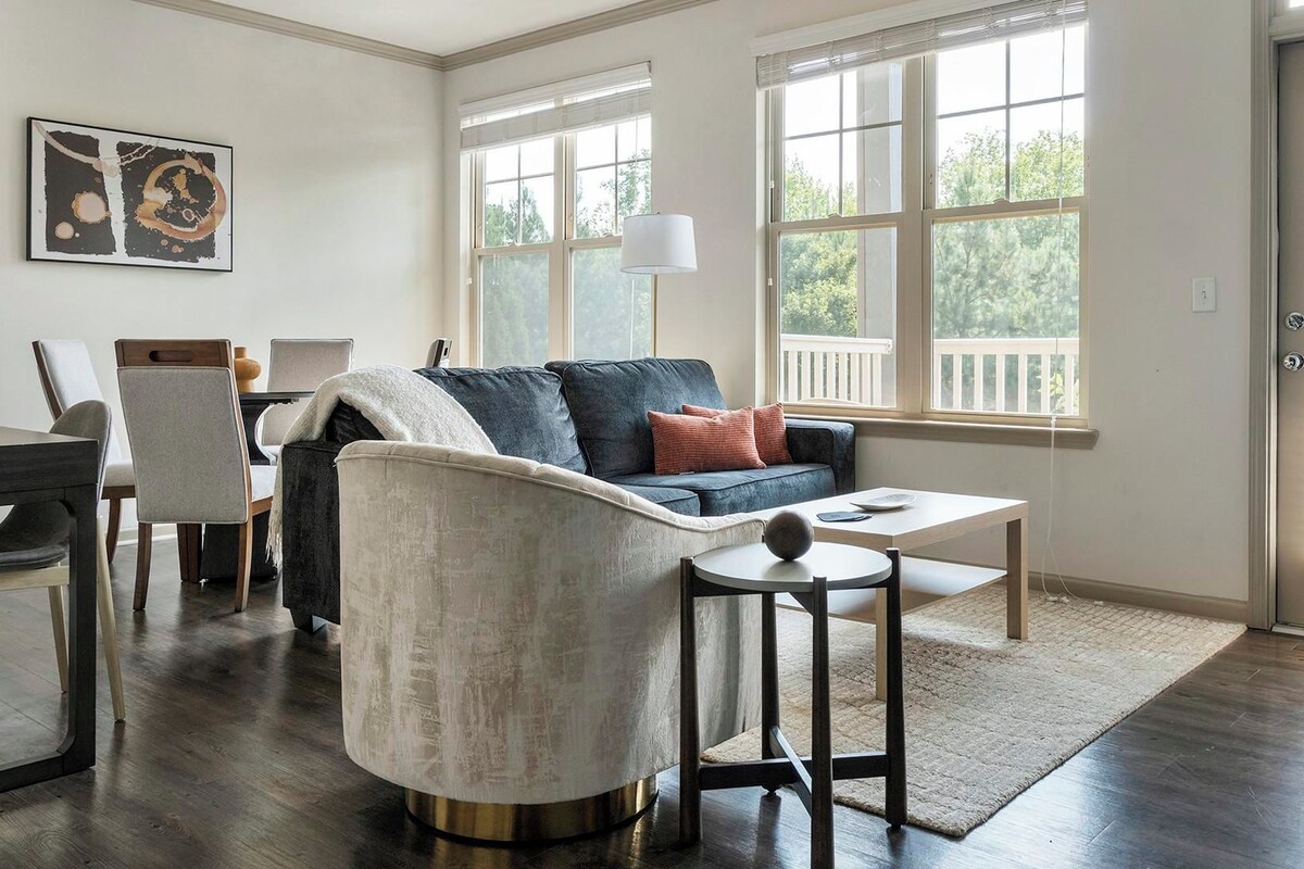 A modern living room with a sofa, chairs, a coffee table, and a dining area.