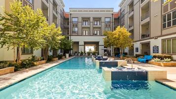 A swimming pool with a 4 ft. deep end, surrounded by lounge chairs and trees.