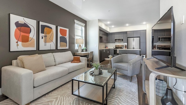 A modern living room with a sofa, armchair, coffee table, and abstract wall art. - Landing Amazing 2bd, Rooftop Lounge, Clubhouse (Fort Worth)