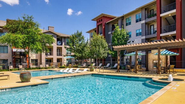 A swimming pool with lounge chairs and a pergola, surrounded by multi-story buildings with balconies. - Landing Chic 1bd, Pool, Gym (Austin)