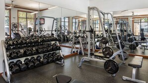 A gym with exercise equipment, weight racks, and a mirror wall. - Landing Chic 1bd, Pool, Gym (Austin)