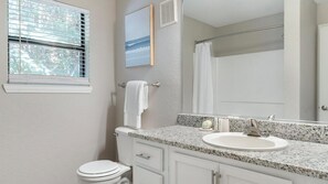 A bathroom with a toilet, sink, mirror, and shower curtain. - Landing Chic 1bd, Pool, Gym (Austin)