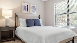 A bedroom with a bed, a nightstand, a lamp, and two framed artworks on the wall. - Landing Chic 1bd, Pool, Gym (Austin)