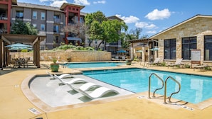 A pool area with multiple swimming pools, lounge chairs, and a covered seating area. - Landing Chic 1bd, Pool, Gym (Austin)