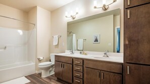 A bathroom with a shower, toilet, vanity with a mirror, and cabinets. - Landing Amazing 1bd, Yoga Studio, Game Room (Punta Gorda)