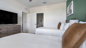 A hotel room with a bed, a dresser, a television, and a door leading to a bathroom. - Landing Amazing 1bd, Yoga Studio, Game Room (Punta Gorda)