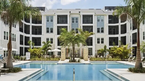 A hotel with a central swimming pool, surrounded by palm trees and lounge chairs. - Landing Amazing 1bd, Yoga Studio, Game Room (Punta Gorda)