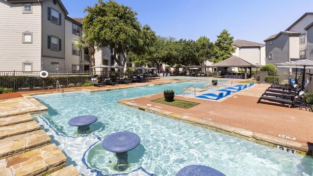 A swimming pool with lounge chairs and a stone deck. - Landing Beautiful 1bd, Gym, Clubhouse (Houston)
