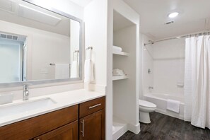 Ein modernes Badezimmer mit großem Spiegel, Waschbecken, Toilette und Duschbereich.