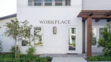 A building with a sign reading 'WORKPLACE' above the entrance, a wooden pergola, and a small tree in the foreground.