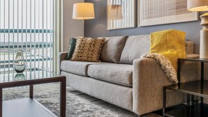 A modern living room with a sofa, two lamps, and framed artwork on the wall. - Landing Amazing 1bd, Pool (Katy)