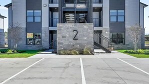 A multi-story building with a prominent entrance, a staircase, and a parking area marked 'RESERVED.' - Landing Amazing 1bd, Pool (Katy)