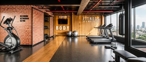 A gym with exercise equipment, motivational wall quotes, and a city view.