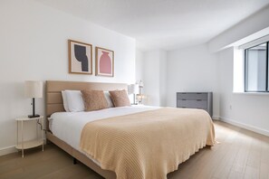 Quarto com cama, mesas de cabeceira, radiador e obras de arte na parede.