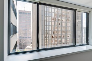 A window with a view of a cityscape, featuring tall buildings and a clear sky. - Blueground | Financial District, pool, nr Boston Common (Boston)