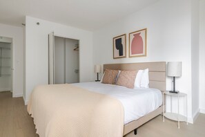 A bedroom with a bed, bedside tables, a wardrobe, and two wall-mounted artworks. - Blueground | Financial District, pool, nr Boston Common (Boston)