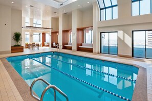 Uma grande piscina interior com pistas demarcadas, área de estar com vista e design moderno.
