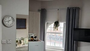 A small, modern kitchen with a refrigerator, a clock, and a window with curtains. - #68 Stylish Digbeth Studio 10 Apt City Centre (West Midlands)