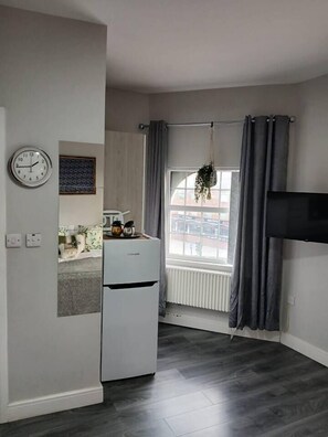 A small, modern kitchen with a refrigerator, a clock, and a window with curtains. - #68 Stylish Digbeth Studio 10 Apt City Centre (West Midlands)