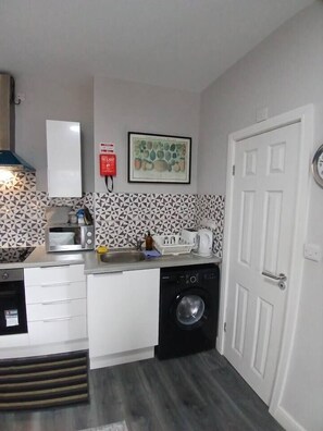 A compact kitchen with a microwave, toaster, sink, and washing machine. - #68 Stylish Digbeth Studio 10 Apt City Centre (West Midlands)