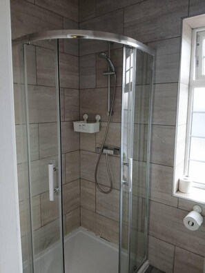 A glass-enclosed shower stall with a white towel rack and a toilet paper holder on the wall. - #68 Stylish Digbeth Studio 10 Apt City Centre (West Midlands)