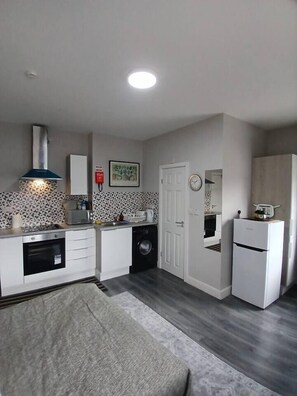 A compact kitchen with a built-in oven, a washing machine, and a refrigerator. - #68 Stylish Digbeth Studio 10 Apt City Centre (West Midlands)